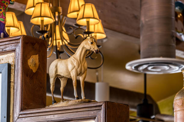 istock Decorative and ornamental yellow ceramic horse, inside a restaurant or office, illuminated with yellow light from a lamp in the background 2150488738