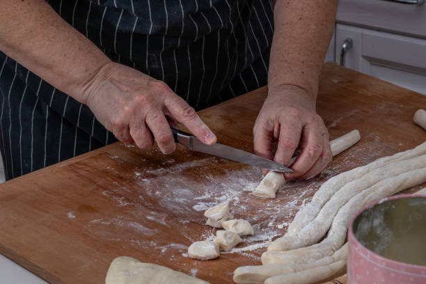 istock Female hands knead the dough and cut it on a wooden table 2150490212