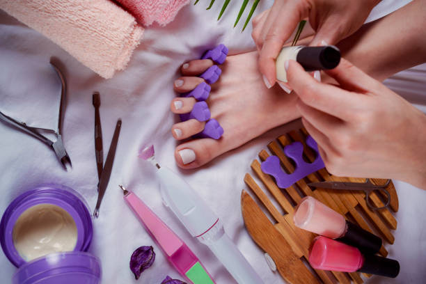 istock Applying pedicure to woman's feet with white toenails, with toe separators 2150495385