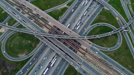 Urban veins: Drone footage over highway interlaced, reflecting non-stop flow of city traffic. Vehicular ballet on multi-level highways, aerial shot captures urban rhythm. Highway concept.