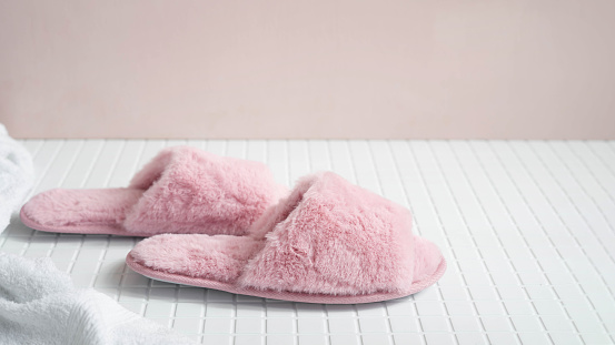 Fluffy slippers on the floor in a pink bathroom.