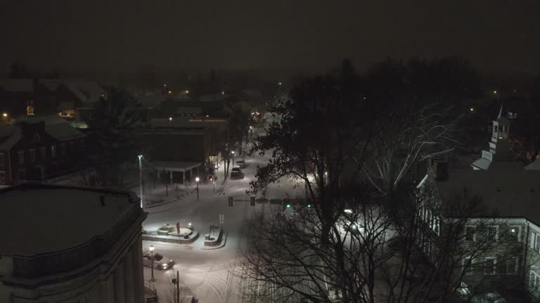 Aerial shot above a snowy road in downtown Lititz at night looking towards the square.