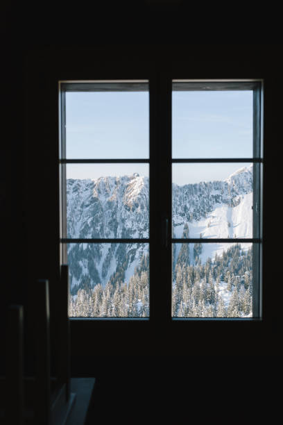 istock View through window to snowcapped mountain and forest 2150507710