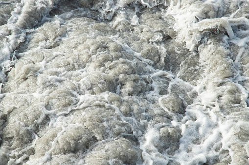 Wild and fast moving river rapids . Water waves texture background