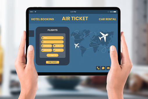 A traveler uses a tablet with a user-friendly travel booking application, featuring options for hotel reservations, flight tickets, and car rentals, streamlining travel arrangements.