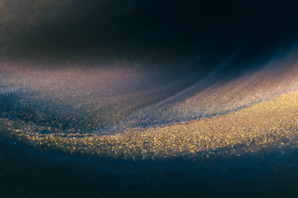 Blue and black acrylic paints with shimmering golden glitter. Liquid paint abstract background. Colorful liquid paint abstract background. Blue and black acrylic paints with shimmering golden glitter blending texture. Macro image gold layer stock pictures, royalty-free photos & images