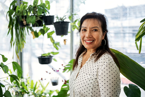 Portrait of cheerful asian senior woman at plant store looking at camera and smiling