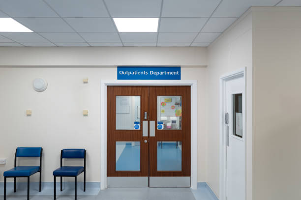 Typical NHS Out Patients waiting room seen in a hospital in England. Typical NHS Out Patients waiting room seen in a hospital in England. Through the double doors are various treatment clinics and doctor's consulting rooms. Hospital stock pictures, royalty-free photos & images