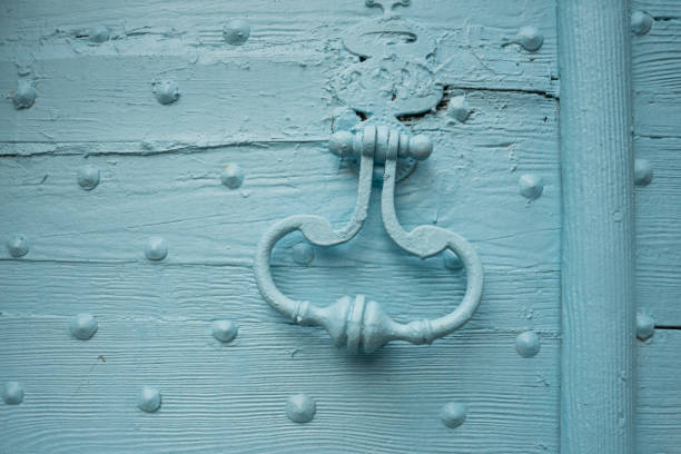 An old wooden door painted blue, with nails and a knocker
