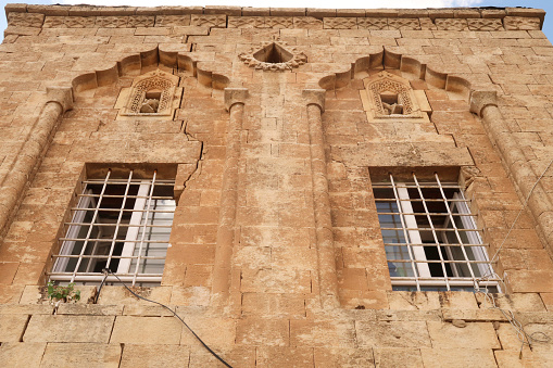 Two windows on the facade of a traditional house in the old town of Mardin, decorated with elaborate carved patterns and details, Mardin, Turkey 2022