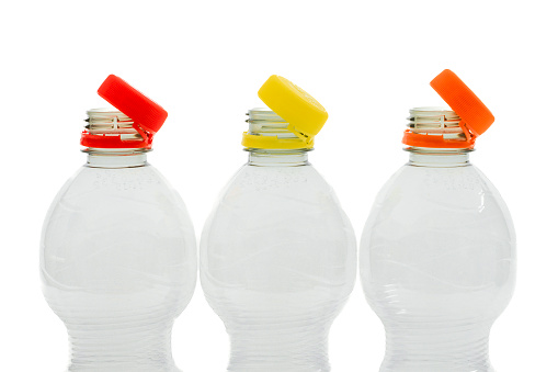 Red, yellow and orange colered tethered caps on 3  plastic bottles isolated on white background