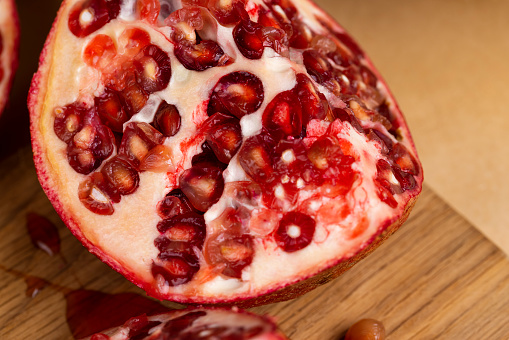 juicy pomegranate on a wooden board, ripe red pomegranate cut into pieces