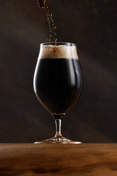 istock Drops odf beer falling into a glass with dark beer. 2150529188