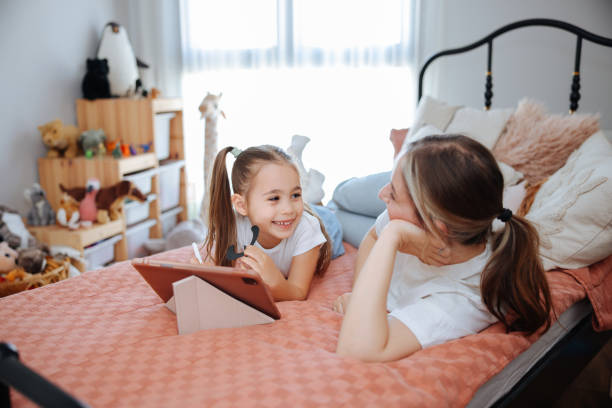 istock Mother and daughter watching their digital tablet together lying in bed 2150529524