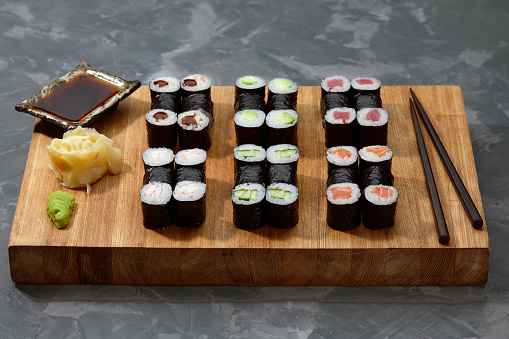 Top view background with set of colorful different kinds of sushi rolls placed on wooden board.