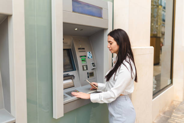 istock Beautiful young woman using the ATM 2150532049