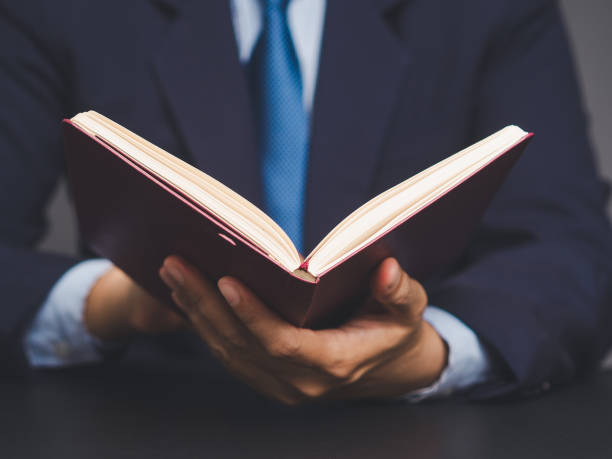 istock Businessman reading a book while sitting at a desk. 2150533530
