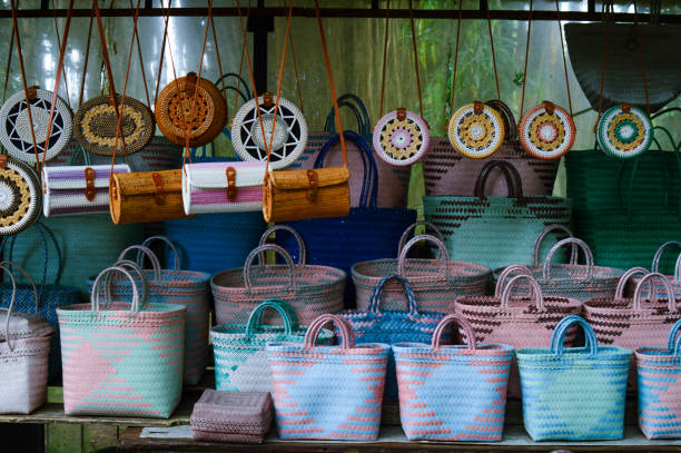 There are colorful woven bags on the table and some are hanging and ready to be sold