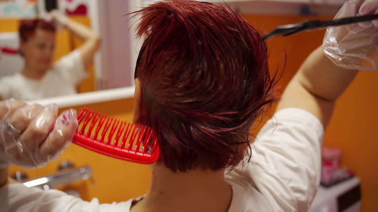 Senior woman dyeing her hair in red color