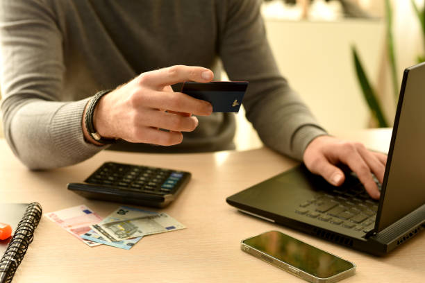istock male hands with a bank card in their hands enter data into a laptop. 2150534317