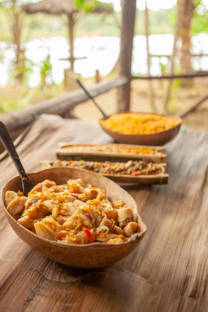 Dishes of  gourmet food on a wooden table, in gourds and bamboo halves  - a gourmet version of traditional food - beans, rice, plantains and rice - in a rural setting.
