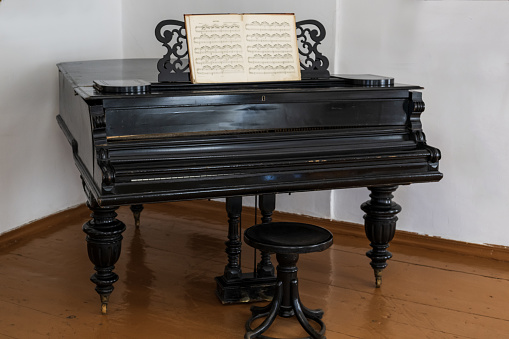 An old black piano on a wooden floor