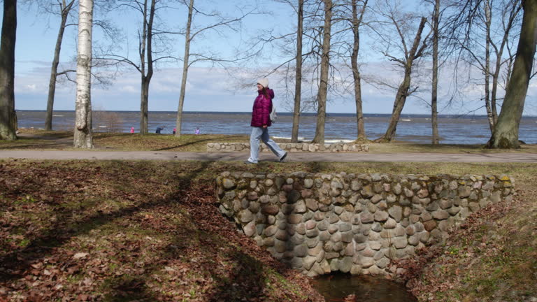 Woman walking on ancient cobblestone bridge with sea in background
