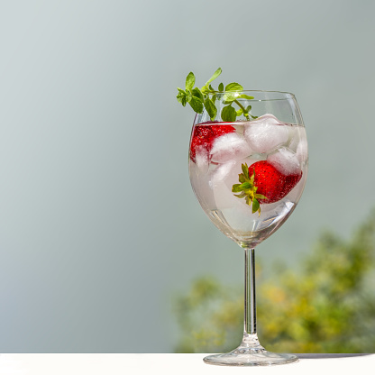 glass of sparkling water with ice and strawberries  on a table on a terrace