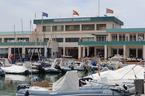Santa Pola, Alicante, Spain, April 27, 2024: Flags flying at the Santa Pola Nautical Club Building at the beginning of the promenade. Santa Pola, Alicante, Spain