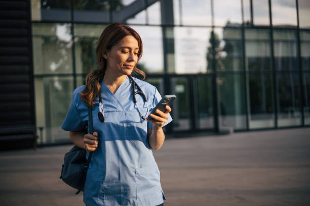 istock Attractive female doctor using smartphone outside. 2150555396