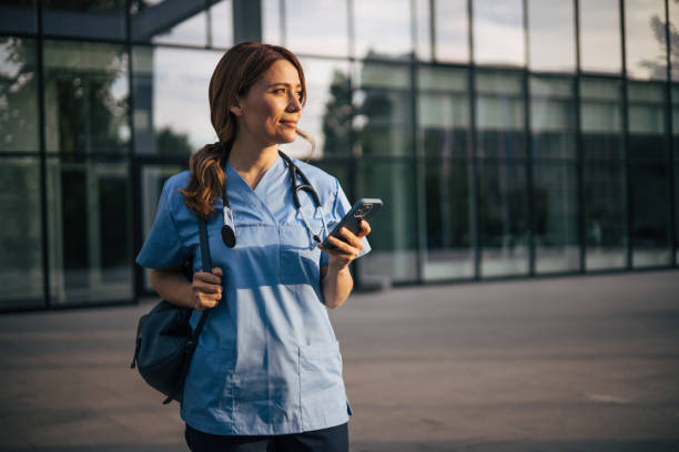 istock Attractive female doctor using smartphone outside. 2150555443
