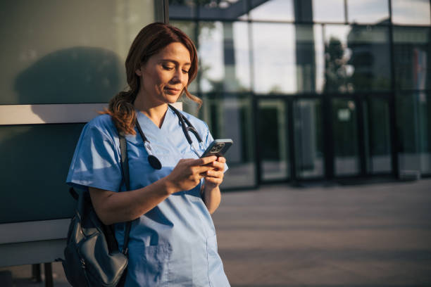 istock Attractive female doctor using smartphone outside. 2150555563