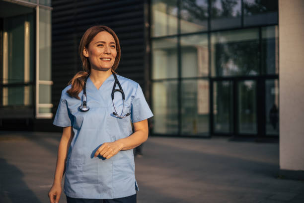 istock Hospital worker standing outside hospital while smiling and looking away. 2150555638