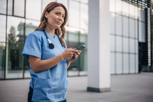 istock Attractive female doctor using smartphone outside. 2150557435