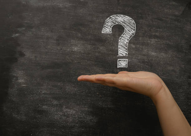 A hand holding a chalkboard with a question mark on it. The chalkboard is on a black background