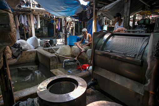 Mumbai, India - March 3, 2024: Men working at Mahalaxmi Dhobi Ghat, the largest open-air laundry in Mumbai, India.