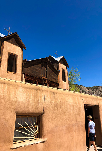 Chimayo, NM, USA. Someone entering Santuario de Chimayo in northern NM, about 30 miles north of Santa Fe. The Catholic church is a pilgrimage site/shrine for folks looking for healing.