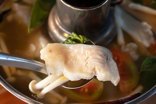 Spicy clear soup with asian redtail catfish and fresh herbs 