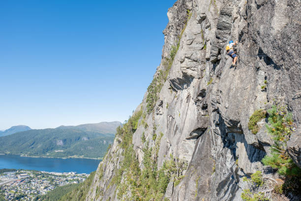 istock Climber Scaling a Steep Cliff with Fjord View 2150571279