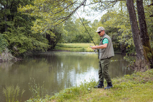 istock Fisherman kneeling on a river bank and successfully catching a fish 2150575353