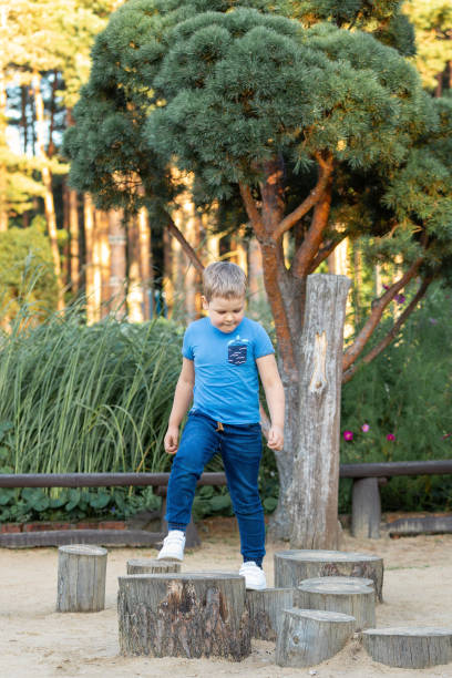 Very focused little boy traveling tree stumps obstacle course