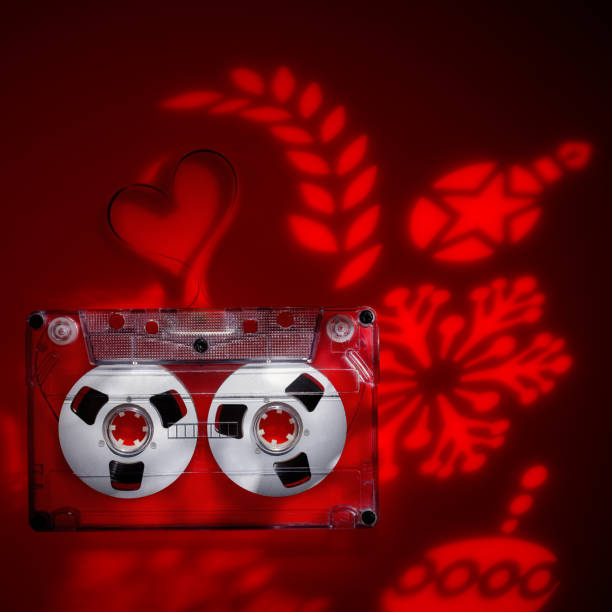 istock Transparent plastic audio cassette, on red acrylic with snowflake light projection, Christmas theme. The picture is suitable for the cover of a collection of Christmas carols 2150578054