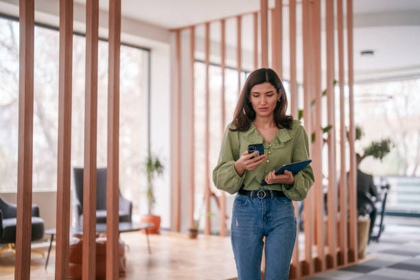 istock Businesswoman using mobile phone and digital tablet in office hall. 2150579736