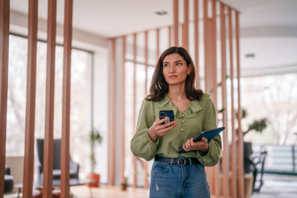 istock Businesswoman using mobile phone and digital tablet in office hall. 2150579789