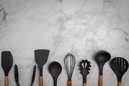 Kitchen silicone utensils for cooking tools on white marble background, top view, flat lay. Kitchenware collection with copy space. Cooking background.