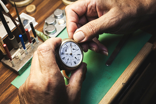 The precise and expert hands of a watchmaker give the final adjustments to the repair of a pocket watch.