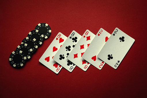 Great luck in the card game of poker with a winning combination of full house or full boat. Playing cards and chips are laid out in a club on a red table.