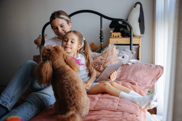 istock Mother and daughter watching their digital tablet together sitting on bed 2150590575
