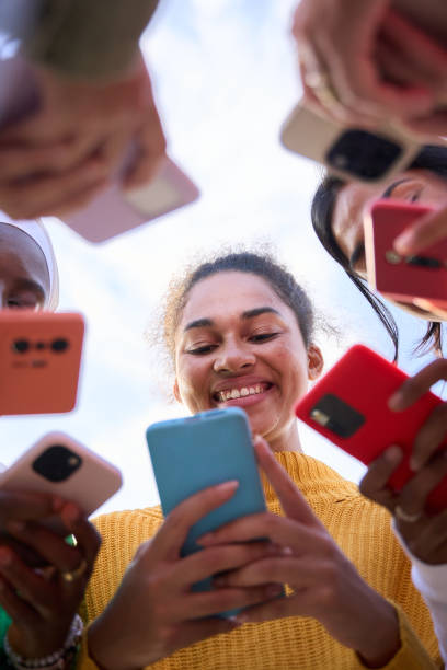 istock Low angle. Group of multiracial young women smiling gathered in circle using mobile phones 2150591221