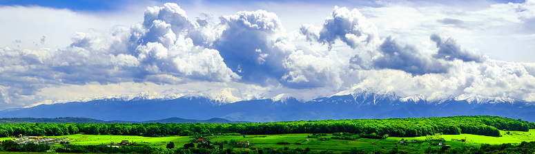 Panoramic spring view of the famous Romanian mountains Fagaras with snow and green grass